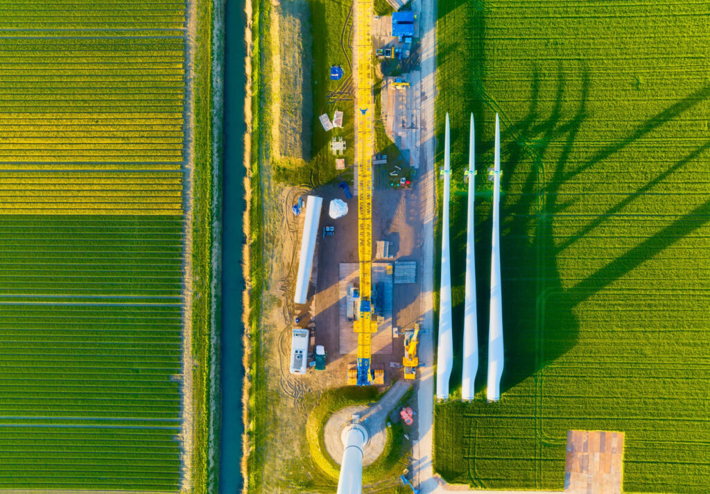 Een veld met windmolens die in elkaar worden gezet